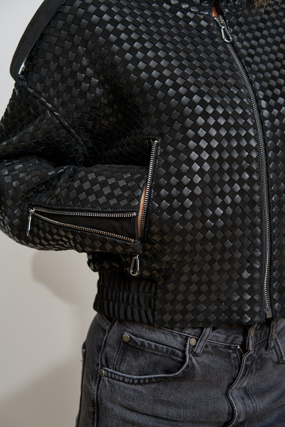 Reißverschlusstaschendetail und elastischer Saum, schwarze geflochtene Lederjacke
